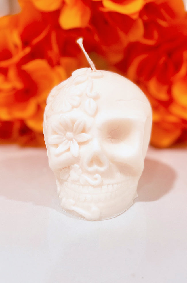 La Catrina Candle: La Catrina sculptural skull candle with floral details, handmade soy wax candle inspired by Día de los Muertos, displayed with marigold flowers.