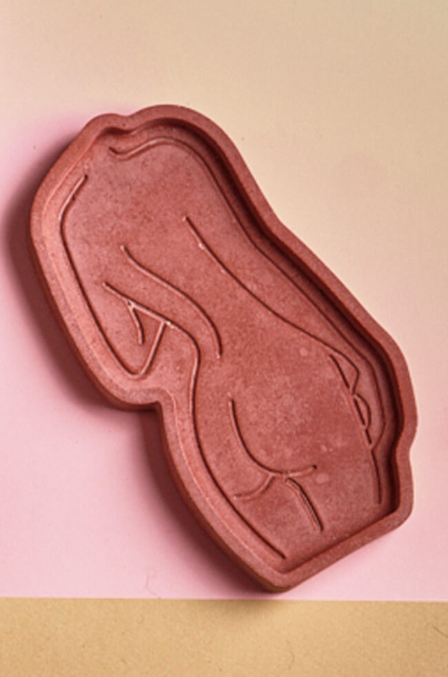 Daring Body Candle Tray: Terracotta sculpted candle tray in the shape of a female silhouette with minimalist line art detailing, placed on a pink surface.