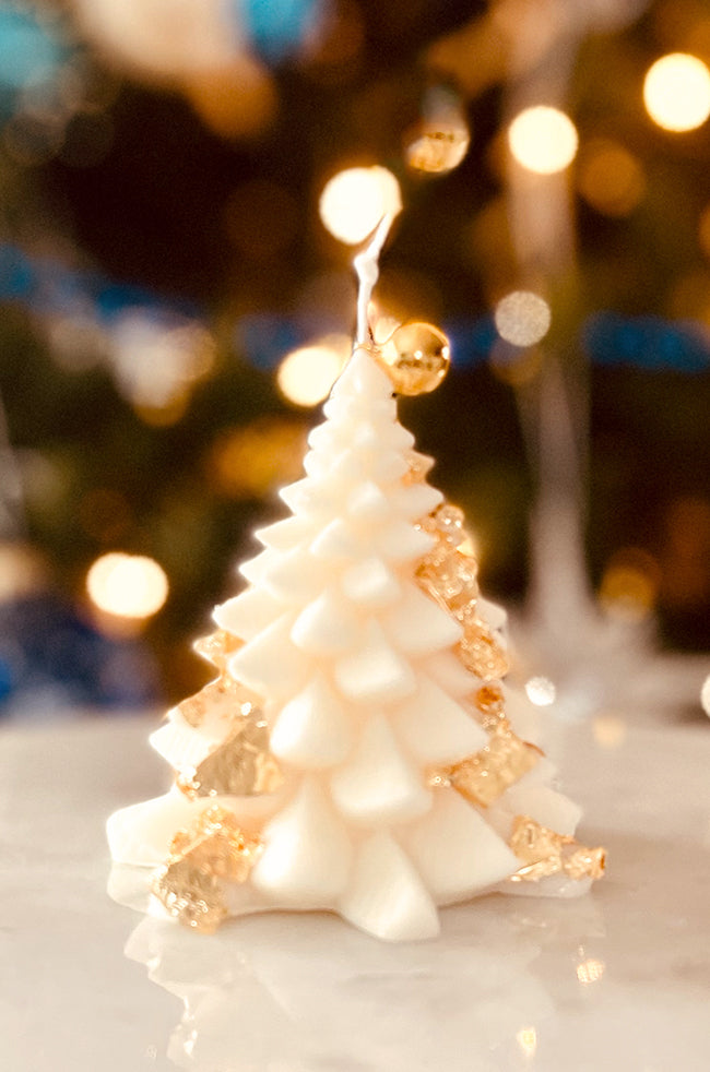 Fiery Tree Small Candle: Elegant small Christmas tree-shaped candle detailed with shimmering gold flakes and topped with a golden ornament, surrounded by festive bokeh lights.