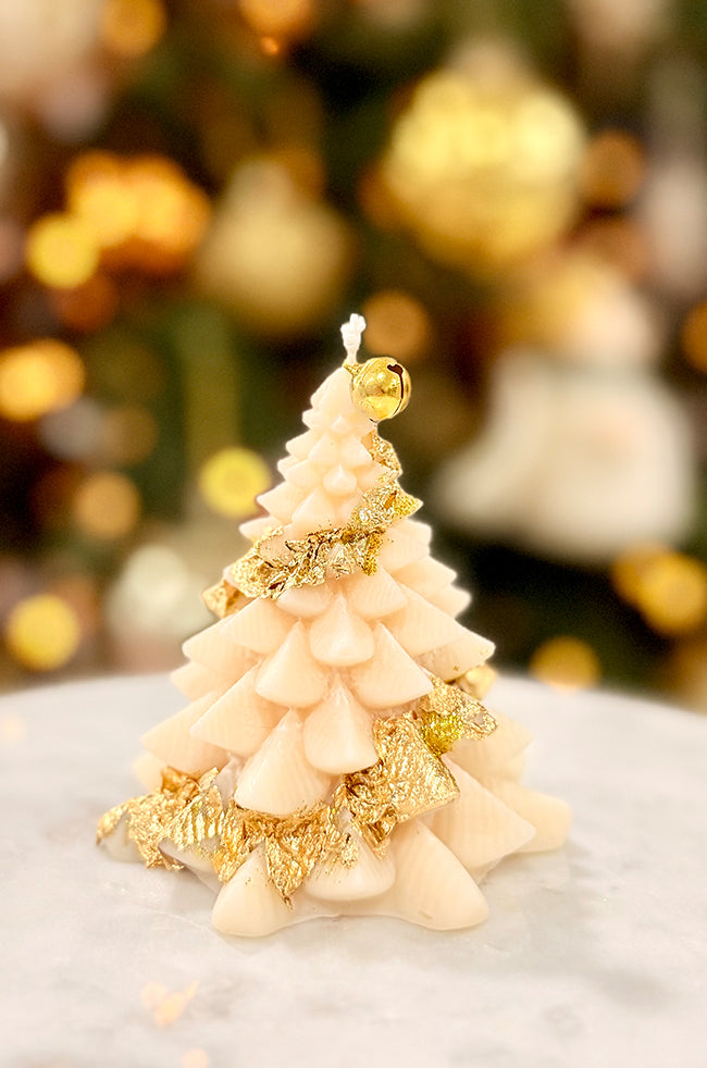 Fiery Tree Small Candle: Sculpted candle shaped like a small Christmas tree, adorned with a golden bell at the top and gold flacks around, set against a softly lit holiday background.