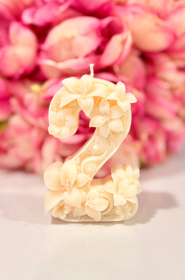 Floral Celebration Number Candle: Ivory floral number 2 celebration candle decorated with roses and delicate botanical details against a pink floral background.