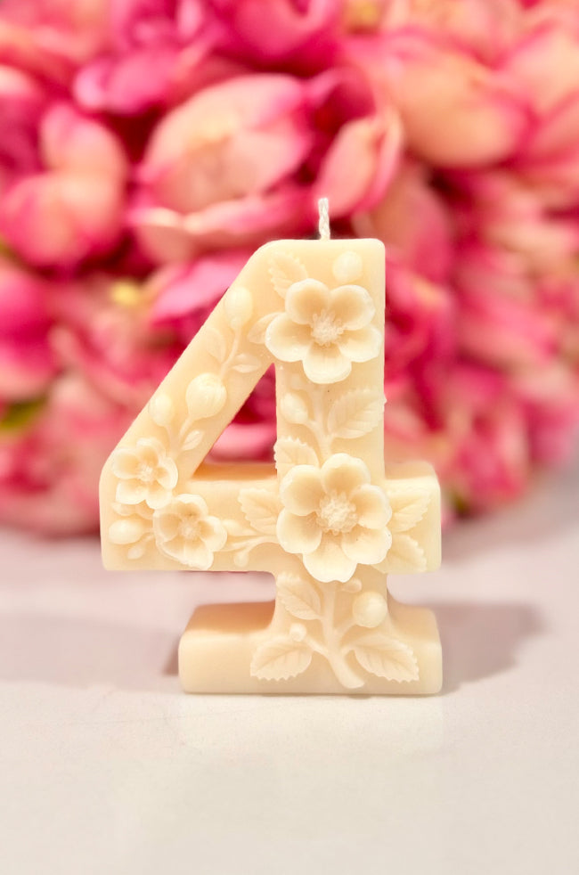 Floral Celebration Number Candle: Ivory floral number 4 celebration candle decorated with roses and delicate botanical details against a pink floral background.