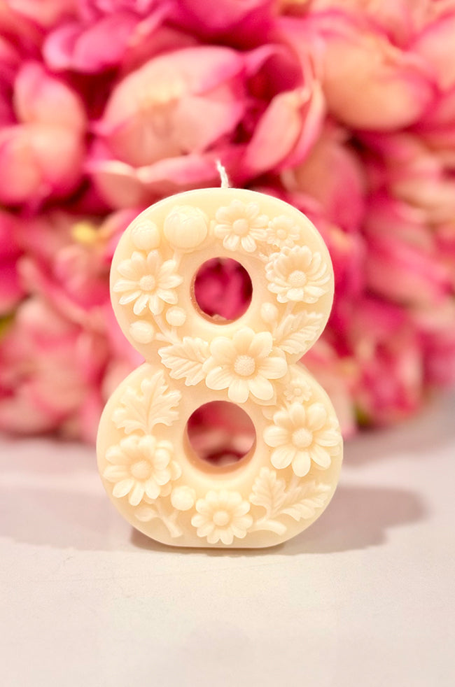 Floral Celebration Number Candle: Ivory floral number 8 celebration candle decorated with roses and delicate botanical details against a pink floral background.
