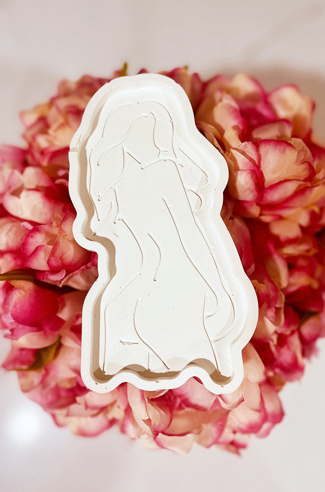 Goddess Silhouette Tray White: White tray with an embossed feminine silhouette design, displayed on a bed of pink flowers.