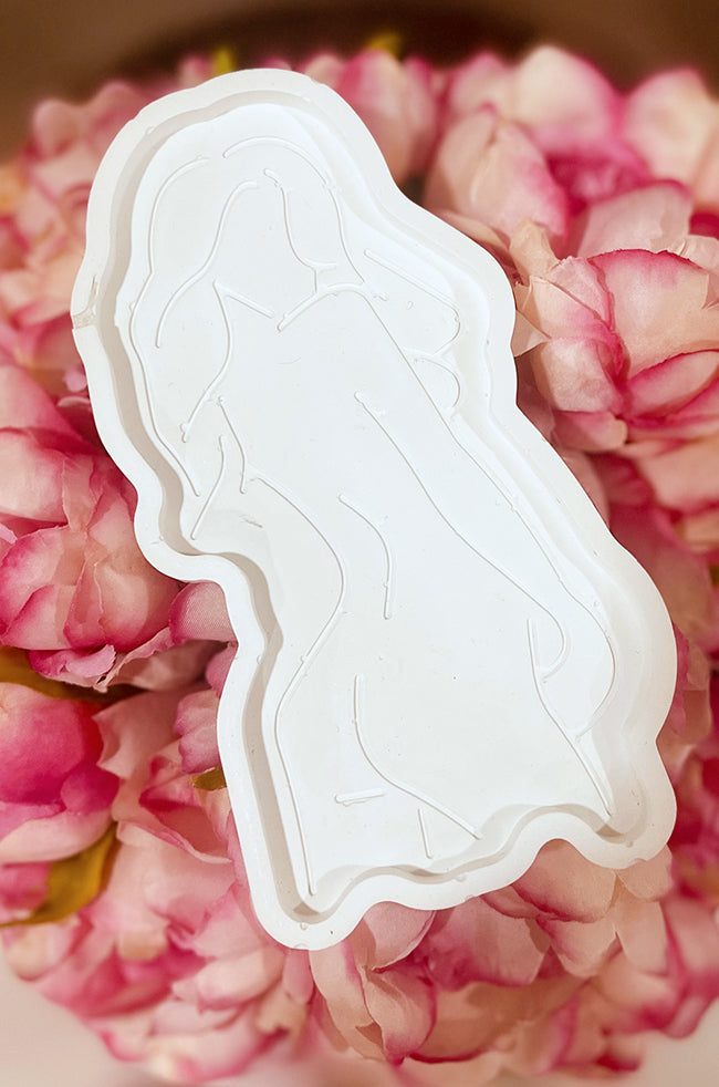 Goddess Silhouette Tray White: White tray with an embossed feminine silhouette design, displayed on a bed of pink flowers.