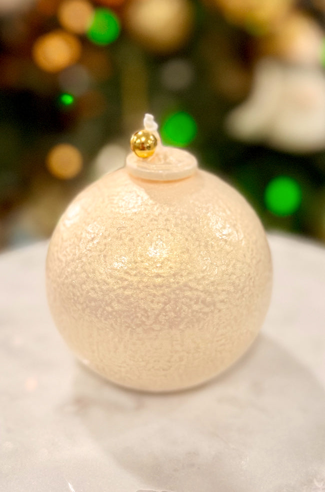 Golden Luxe Ornament: Handmade Golden Luxe Pearl ornament candle featuring a luminous ivory texture and gold bell topper, styled with warm holiday lights.