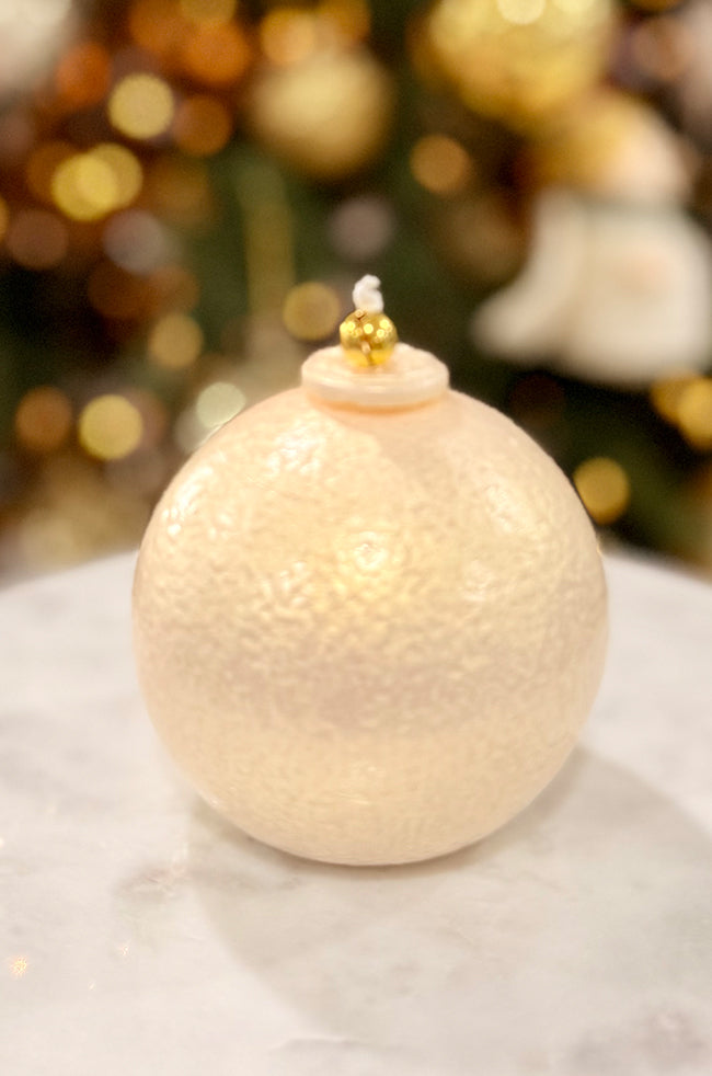 Golden Luxe Ornament: Luxury pearl-toned ornament-shaped candle with a softly textured surface and gold bell top in an elegant holiday setting.