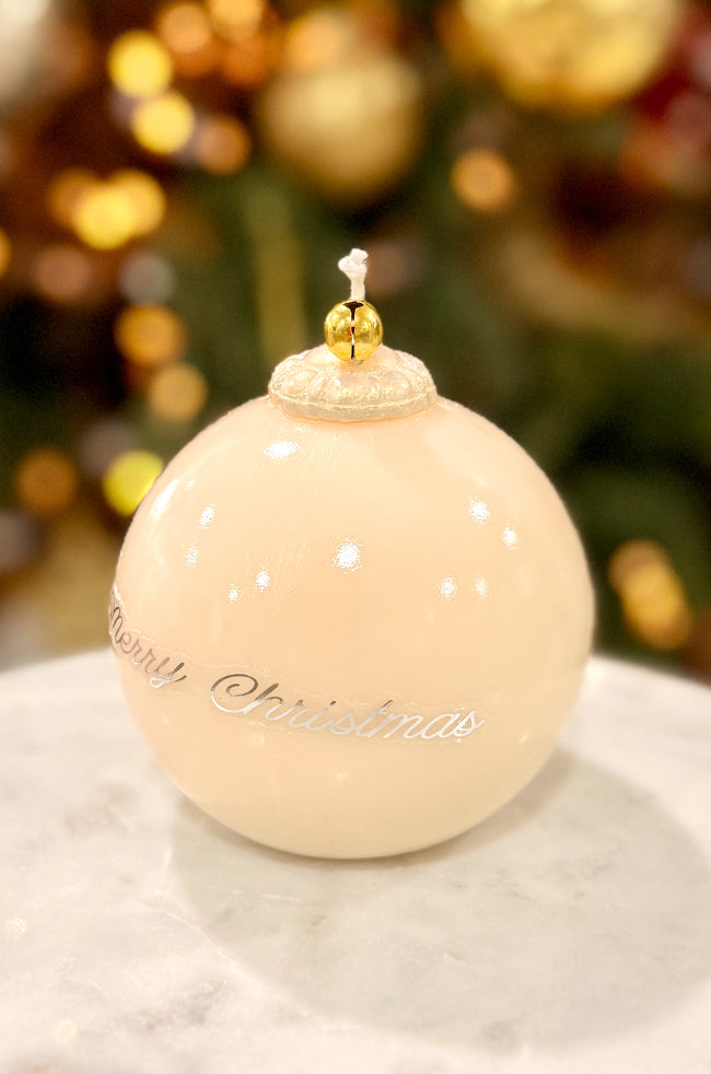Golden Merry Ornament Candle: Handmade ivory ornament candle with smooth varnished surface, gold bell top, and subtle “Merry Christmas” script against a festive background.