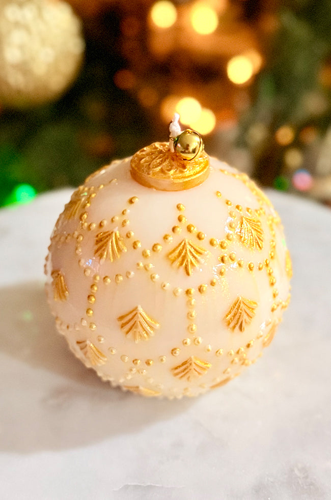 Golden Star Ornament Candle: Elegant round sculpted candle resembling a holiday ornament, decorated with gold leaf patterns and dots, finished with a gold bell and soft shine.