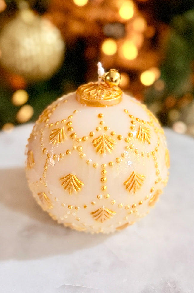 Golden Star Ornament Candle: Close-up of a hand-painted golden ornament candle with delicate bead and arrow detailing, styled in a cozy, warmly lit holiday setting.