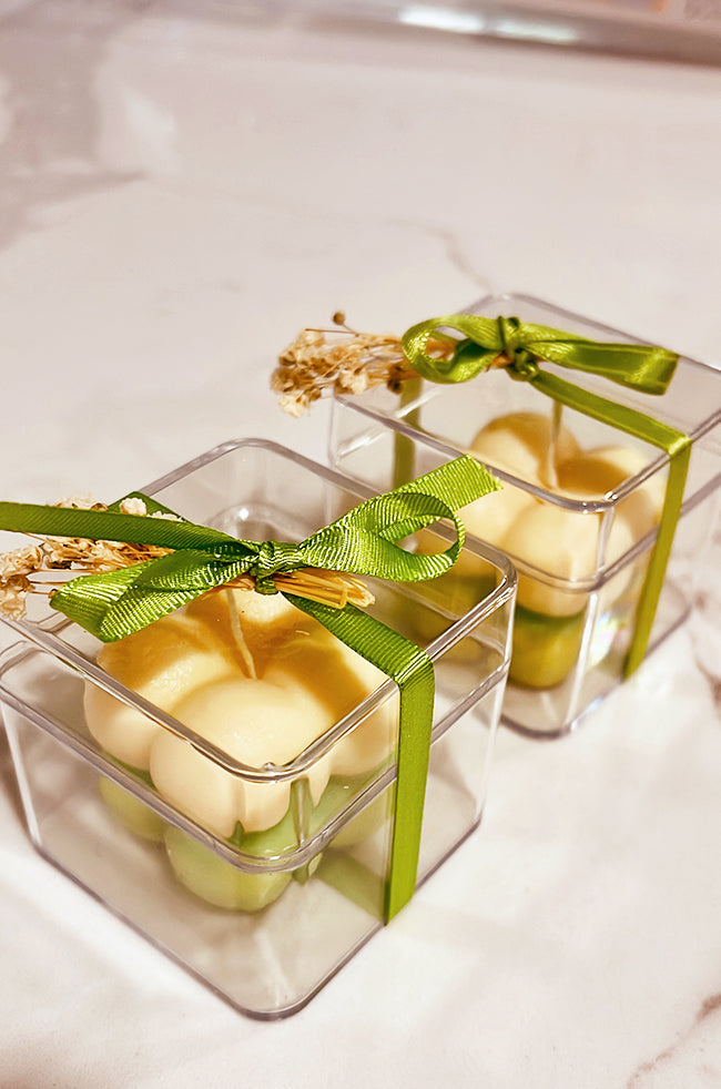 Mini Bubble Candle: Two-toned green and ivory Mini Bubble candles in clear favor boxes with green ribbons and dried florals.