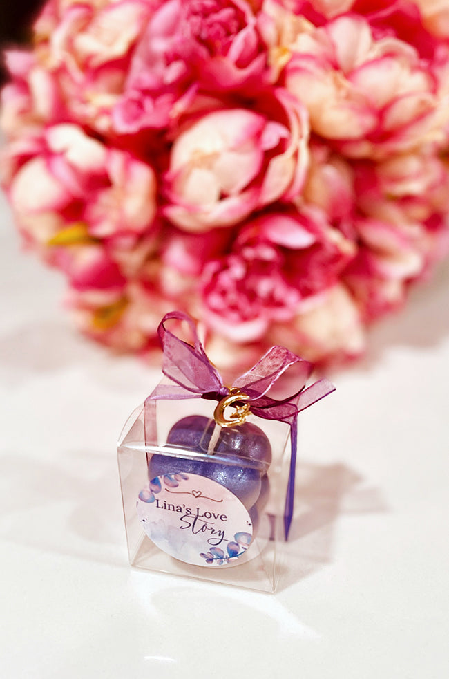 Mini Bubble Candle: Purple Mini Bubble candle favor in a clear box with violet ribbon, gold charm, and custom “Lina’s Love Story” label.