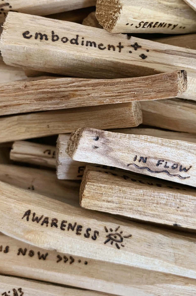 Palo Santo: Close-up of hand-engraved Palo Santo sticks with positive affirmations such as “Awareness,” “Embodiment,” and “Serenity.”