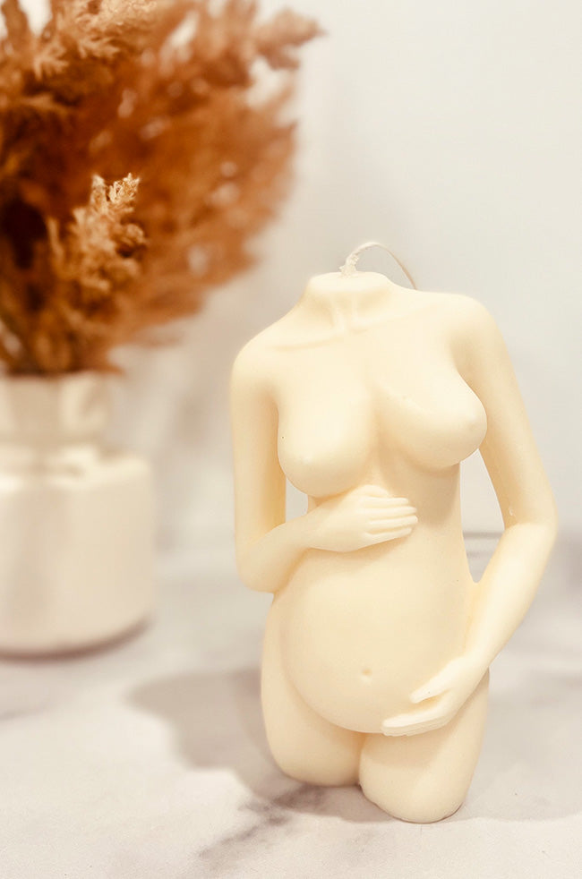 Precious Pregnant Venus Candle: sculptural pregnancy candle in ivory, displayed on a marble surface with neutral floral décor.