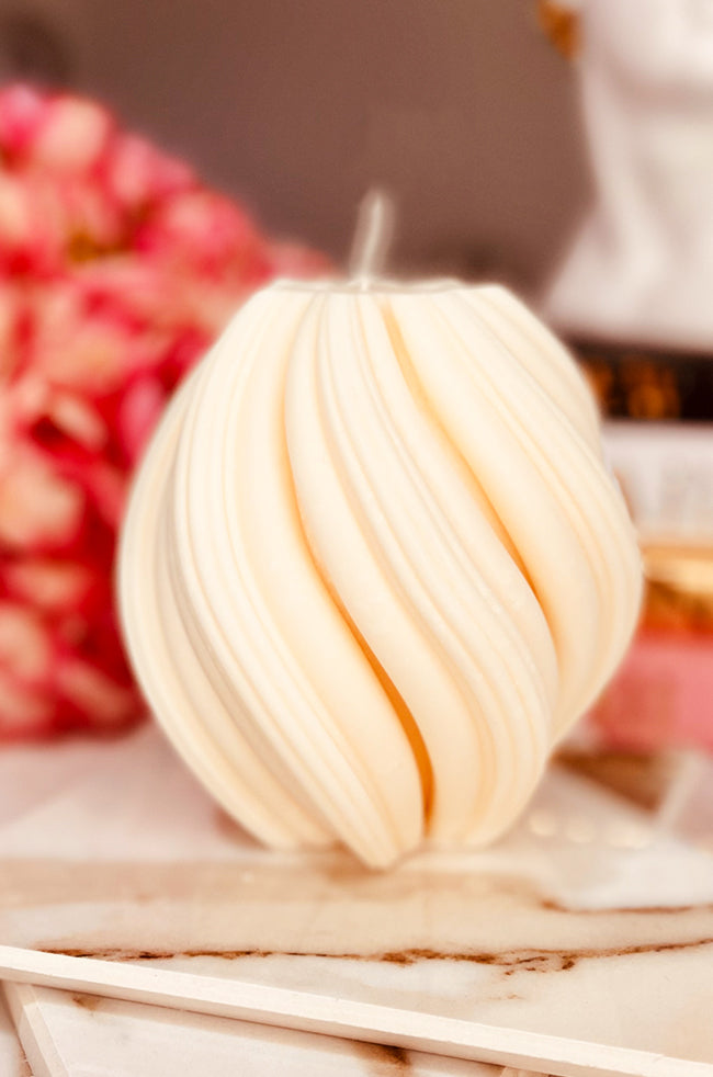 Rising Column Medium Candle: Ivory sculptural candle with a twisting ribbed design displayed on a geometric surface.
