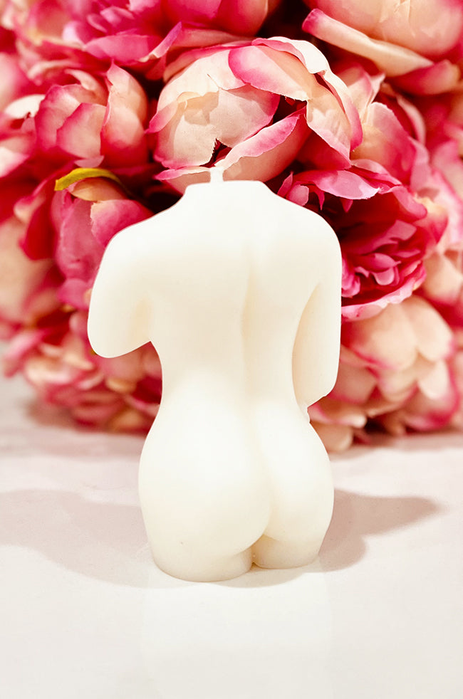Shy Lady Candle: Back view of the ivory Shy Lady body candle highlighting its sculptural silhouette against a pink floral background.