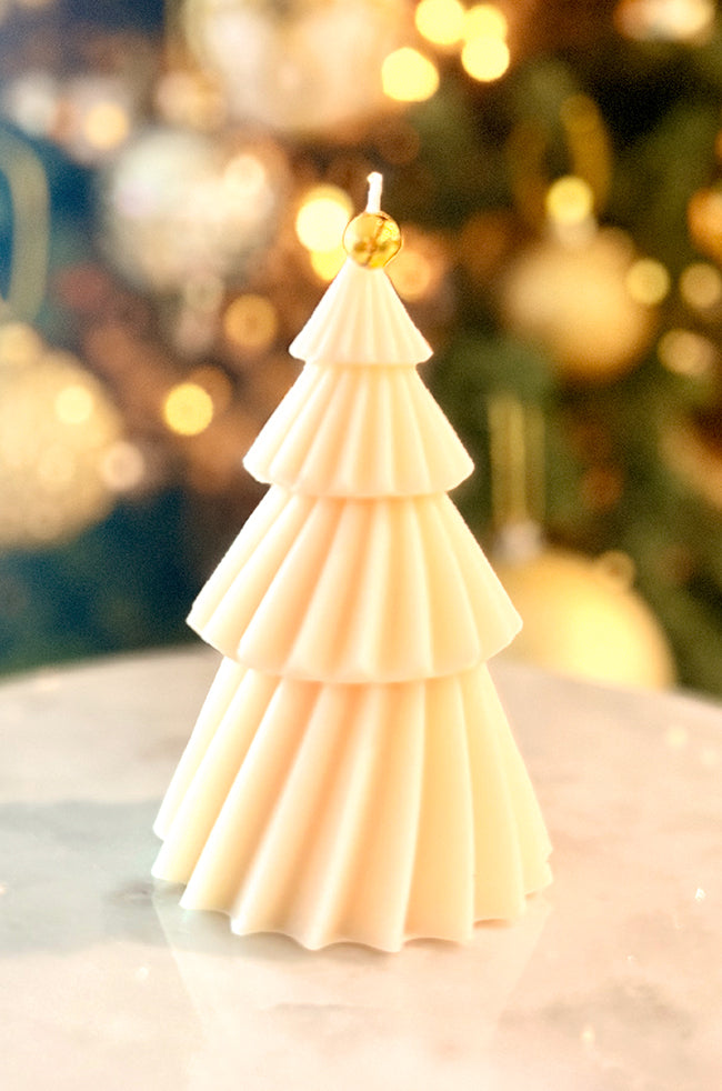 Solstice Tree Large Candle: Luxury tree-shaped candle with gold leaf accents wrapped around its tiers, set against a glowing Christmas backdrop.