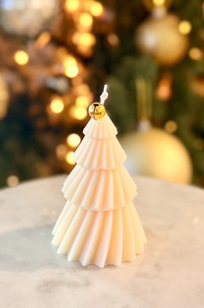 Solstice Tree Small: A small, tiered Christmas tree candle adorned with delicate gold leaf accents, creating a luxurious and festive look, photographed in front of a warmly lit holiday tree.
