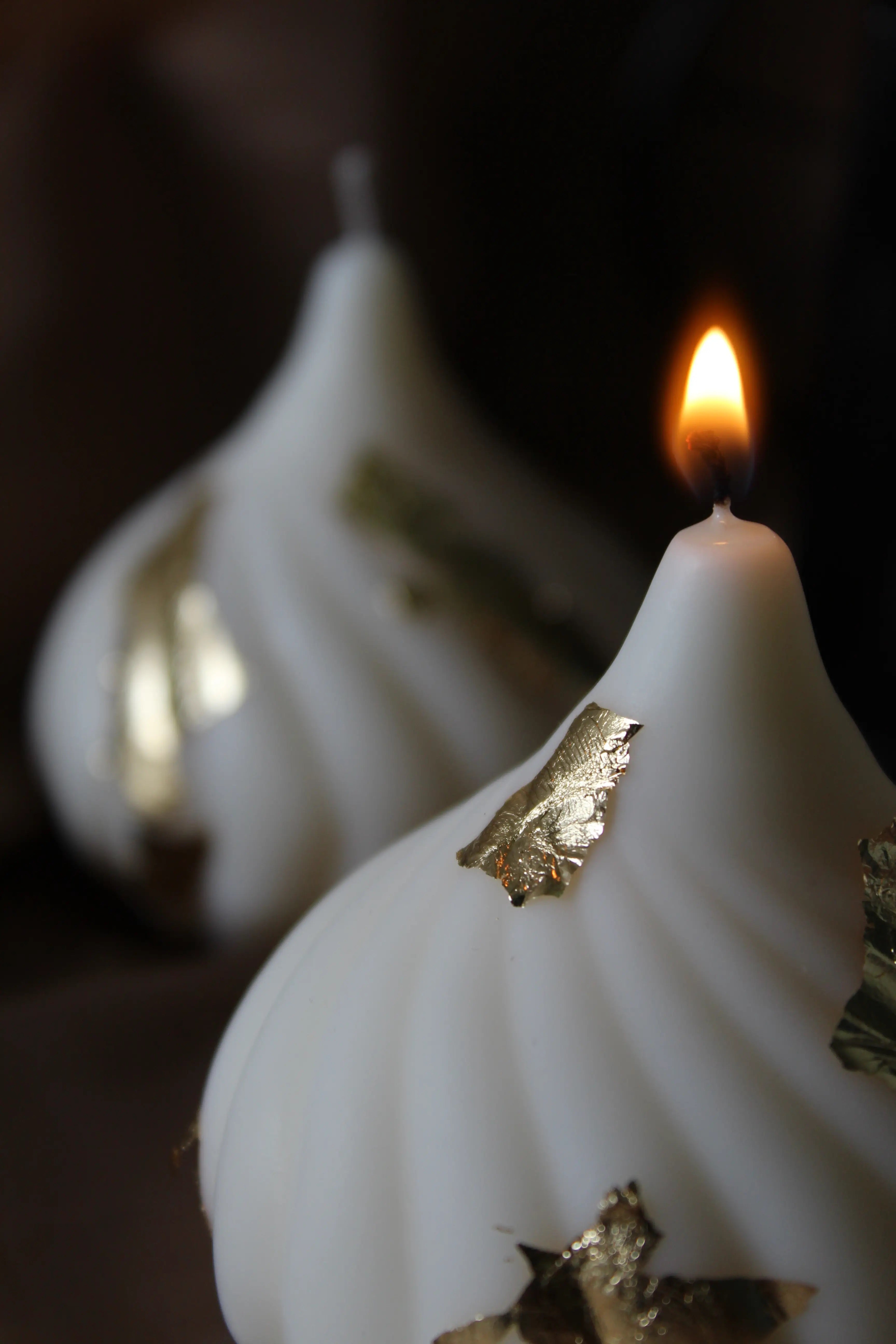Teardrop Candle: Hand-poured Teardrop Candle softly glowing while lit, highlighting its curved shape and refined gold accents for modern interior styling.
