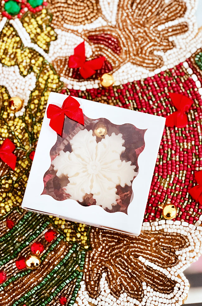 The Christmas Snowflake Candle: Christmas Snowflake candle in a white gift box with clear window, red bow, and festive holiday packaging.