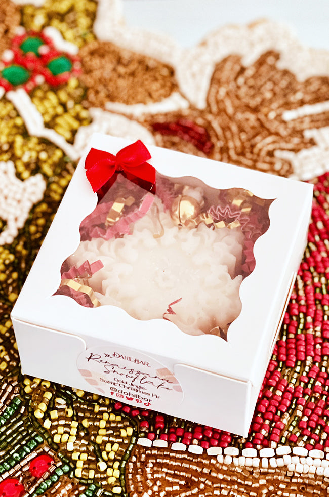 The Renaissance Snowflake Candle: Close-up of the boxed Renaissance Snowflake candle with red bow, clear window, and festive gift packaging.