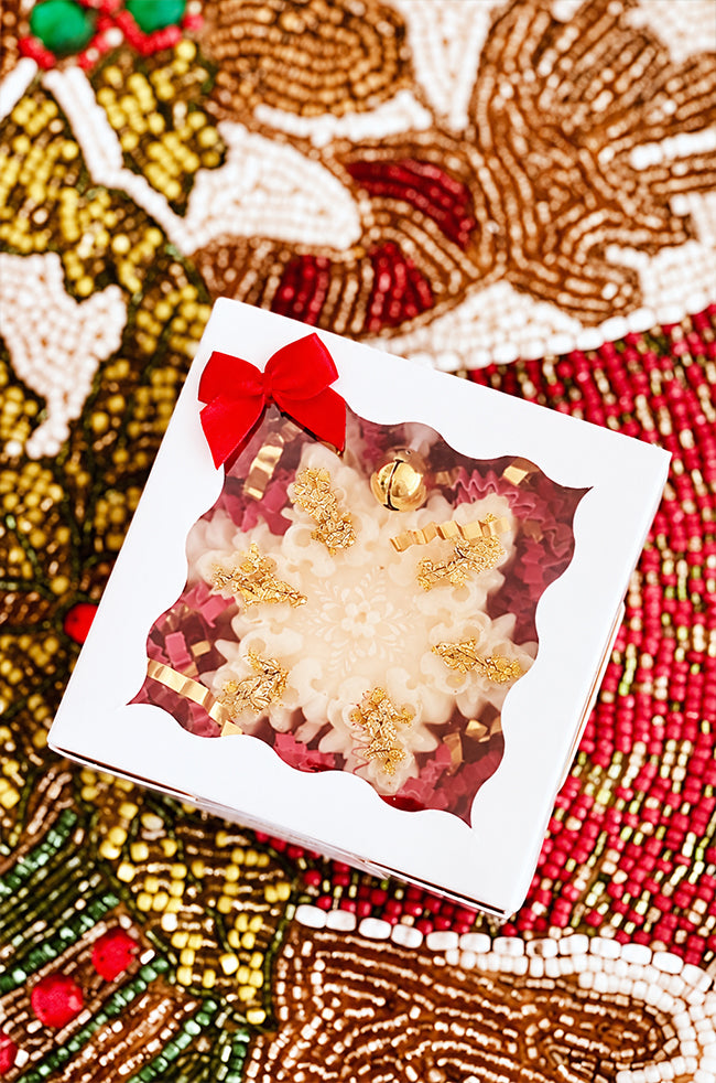The Renaissance Snowflake Candle: Renaissance Snowflake candle with gold flakes and gold bell packaged in a white gift box with red bow.