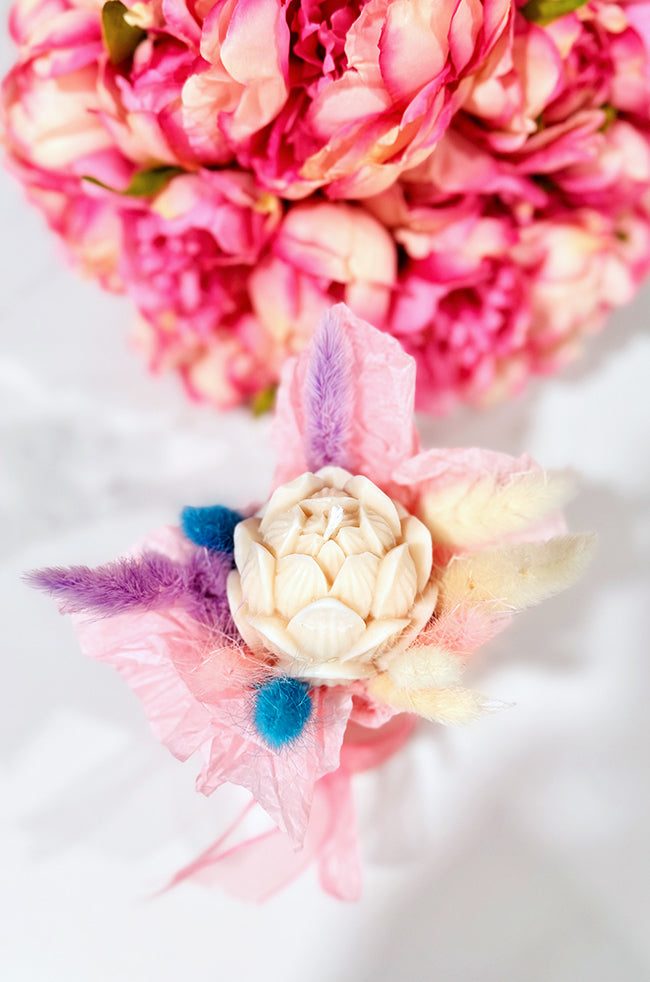 Tulip Glow Candle: Handmade sculptural Tulip Glow candle shaped like a blooming tulip, wrapped with pink and pastel decorative flowers, styled with flowers for luxury home décor.