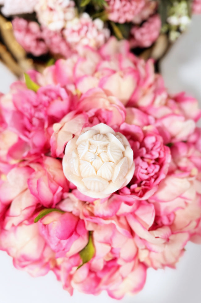 Tulip Glow Candle: A close-up of pink flowers with a white center tulip candle on a blurred floral background