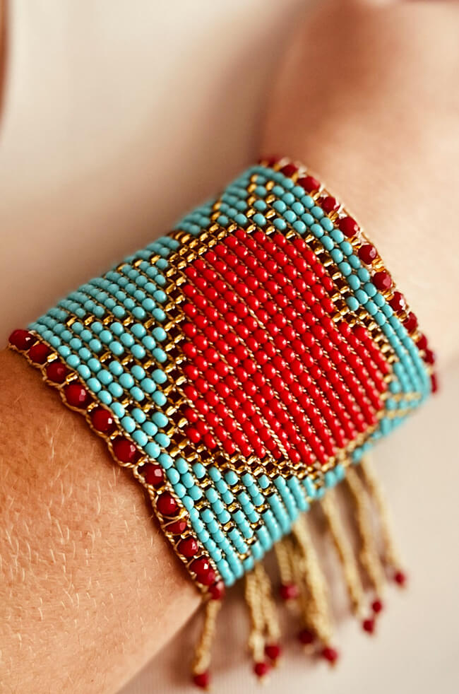 Blue Heart: A handmade beaded bracelet featuring a large red heart design in the center, surrounded by turquoise and gold beads, with red bead accents and dangling gold and red fringe.