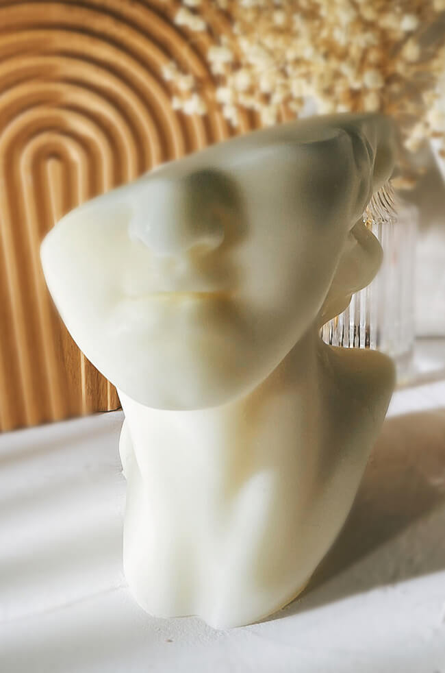 David's Flame: Sculpted white candle resembling a classical male bust with a partially abstract face.