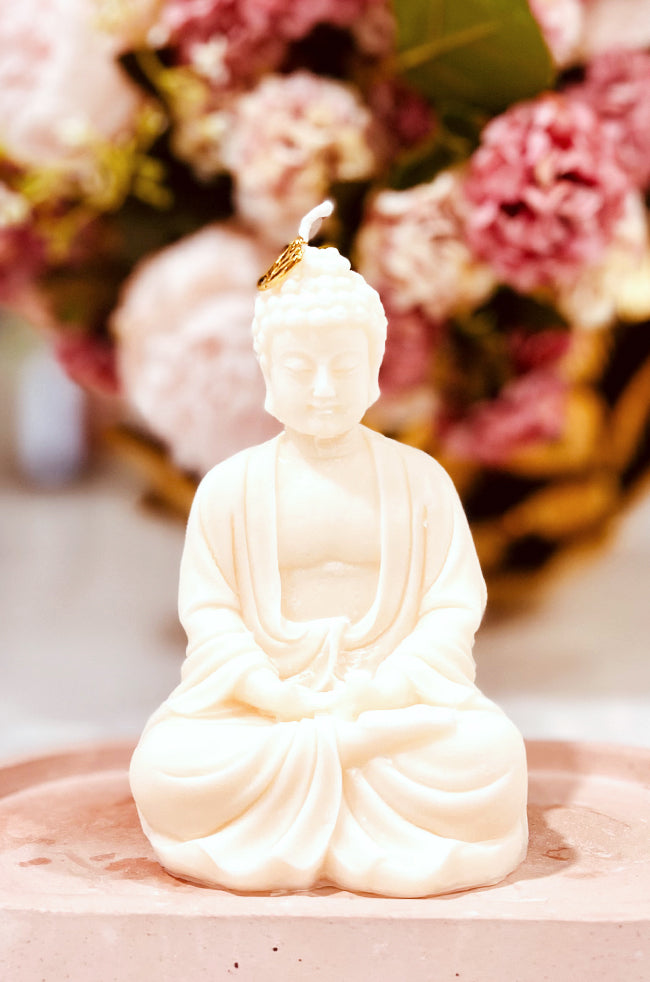 Dhyana Mudra Buddha: Handmade Dhyana Mudra Buddha candle in ivory wax, placed on a minimalist pink tray with floral background—luxury home décor accent.