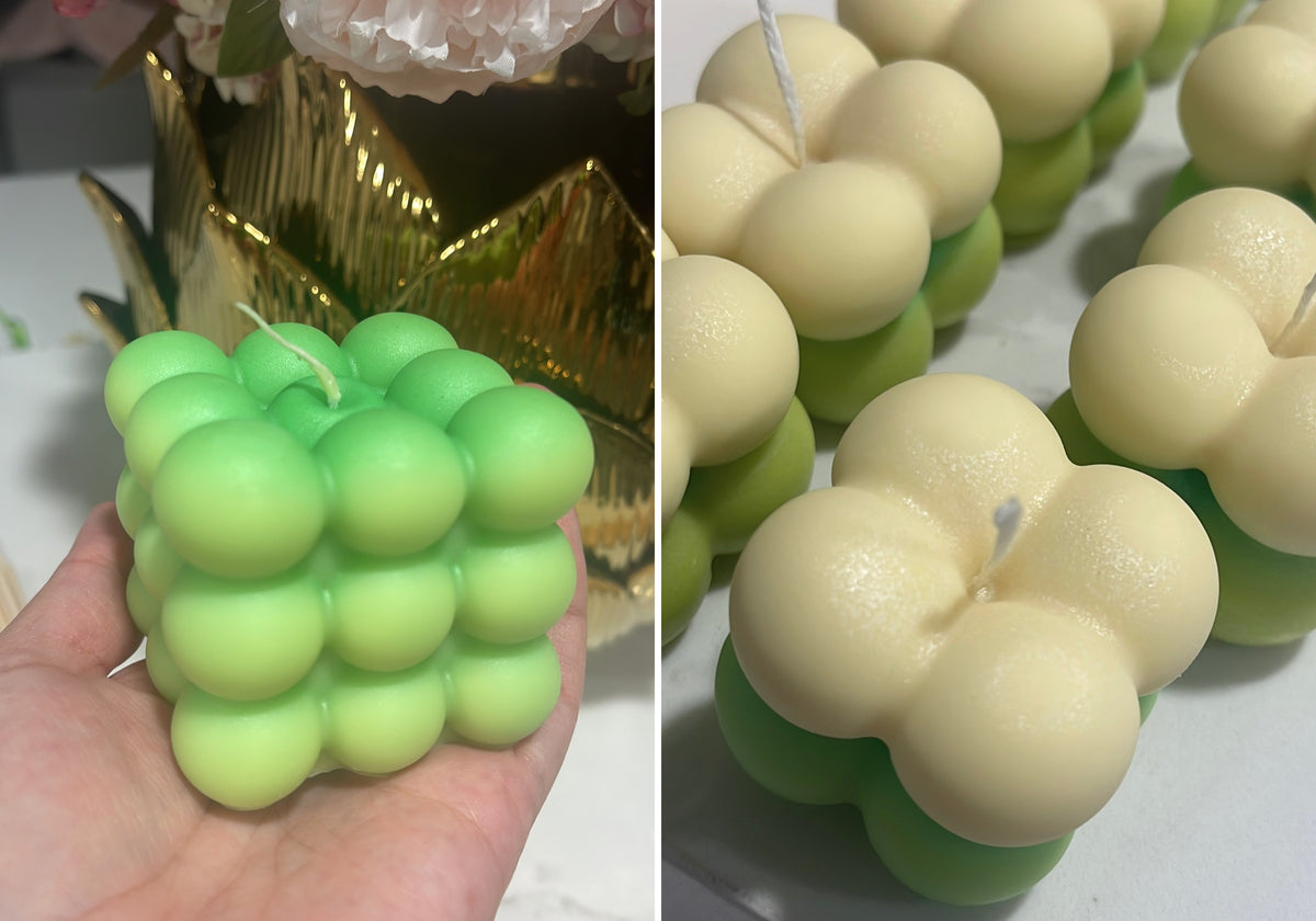 A green Bubble candle held in one hand beside green-and-ivory Mini Bubble candle favors made for Mateo’s baby shower.