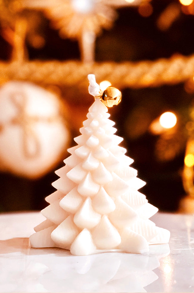 Fiery Tree Small Candle: Sculpted candle shaped like a small Christmas tree, adorned with a golden bell at the top, set against a softly lit holiday background.