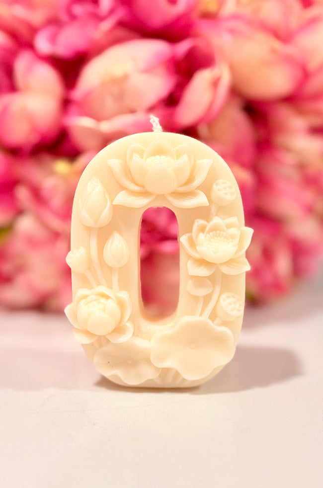 Floral Celebration Number Candle: Ivory floral number 0 celebration candle with sculpted flowers and botanical details, styled against a soft pink floral background.