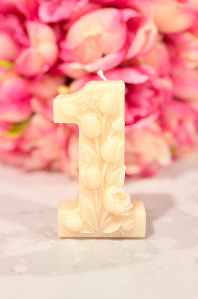 Floral Celebration Number Candle: Ivory floral number 1 celebration candle decorated with roses and delicate botanical details against a pink floral background.