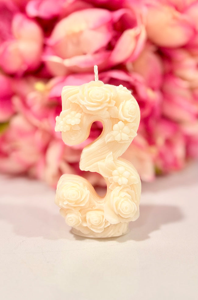 Floral Celebration Number Candle: Ivory floral number 3 celebration candle decorated with roses and delicate botanical details against a pink floral background.