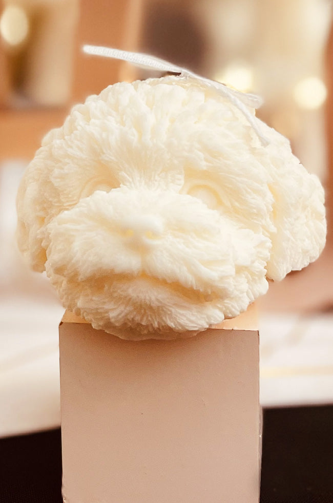 Furry Friend Candle: Ivory dog-shaped sculptural candle with detailed fur texture, topped with a small white ribbon, displayed on a square base.