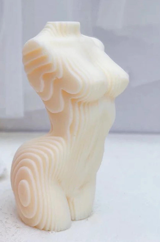 Geometric Venus Candle: Ivory sculptural candle shaped as a stylized female torso with layered geometric contours, displayed on a light surface.
