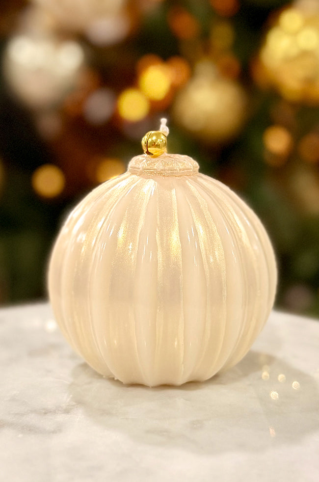 Golden Glow Ornament: Luxury pearl-toned ornament-shaped candle featuring a gentle glow, ribbed design, and gold bell top in a minimalist holiday setting.