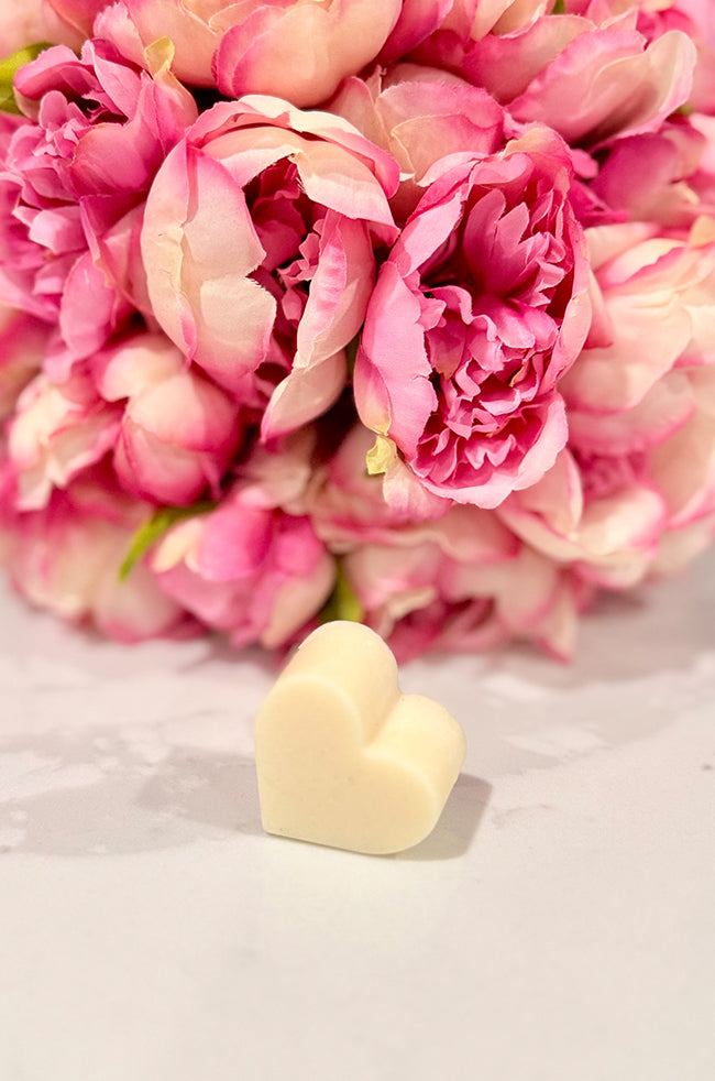 Heart Wax Melts: Single ivory Heart Wax Melt displayed in front of a soft pink floral bouquet.