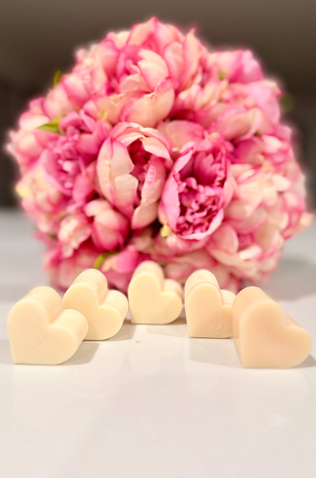 Heart Wax Melts: Assorted ivory Heart Wax Melts displayed with soft pink flowers in the background.