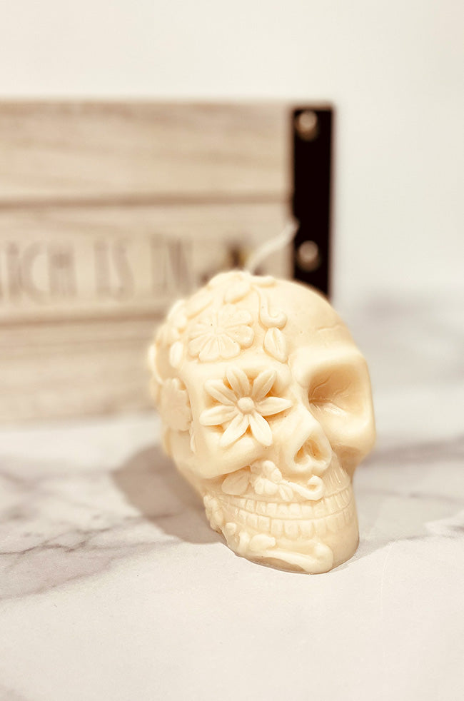 La Catrina Candle: La Catrina sculptural skull candle with floral details, handmade soy wax candle inspired by Día de los Muertos, displayed on marble.