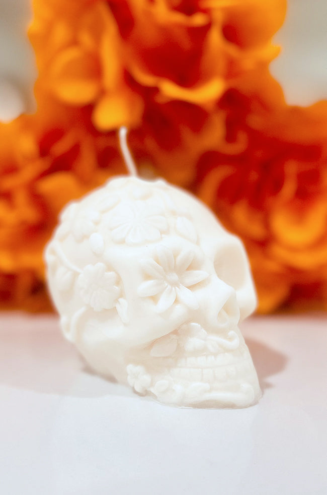 La Catrina Candle: La Catrina sculptural skull candle with floral details, handmade soy wax candle inspired by Día de los Muertos, displayed with marigold flowers.