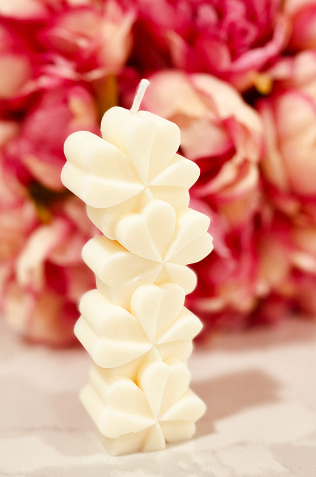 Lucky Clover Candle: Handcrafted Lucky Clover sculpted candle made of eco-friendly wax, featuring a modern four-leaf clover design, perfect for minimalist and luxury home décor in a floral background.