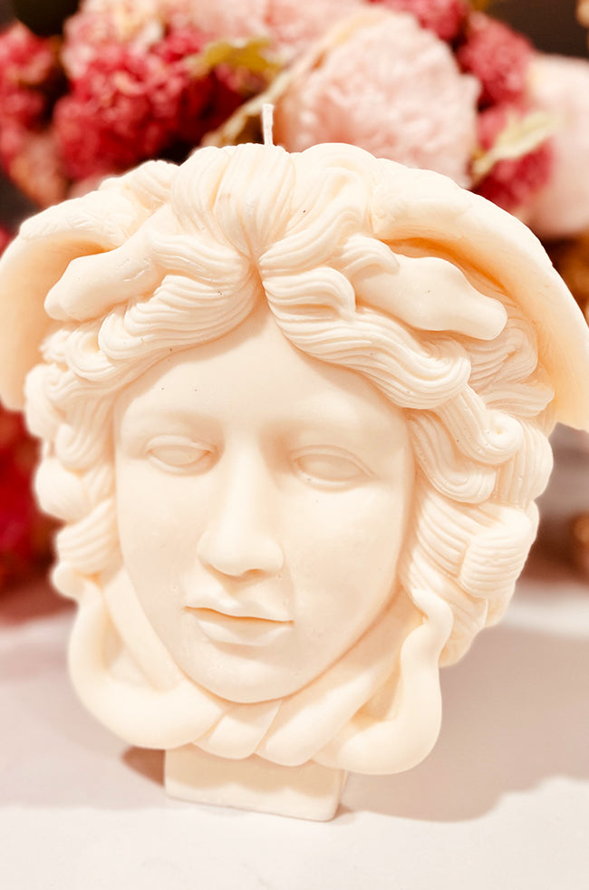 Medusa Candle: Right-profile view of the Medusa candle, capturing the flowing hair, soft facial contours, and coiled snakes wrapping around the base and crown.