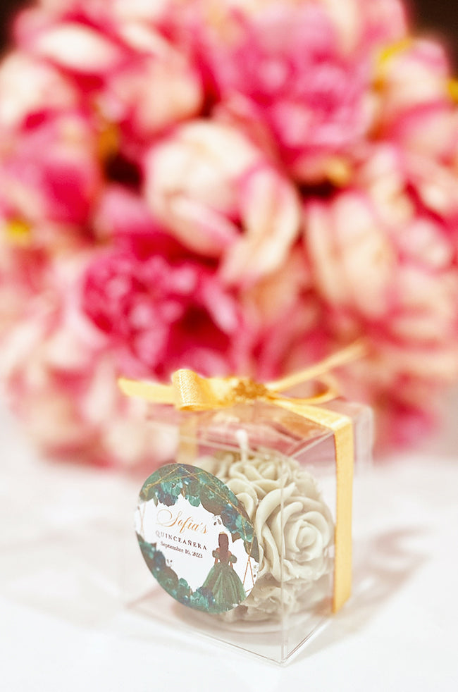 Mini Bloom Gifted Candle: Green Mini Bloom candle favor in a clear box with golden ribbon and a custom quinceañera label.