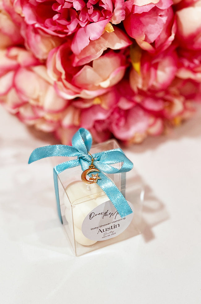 Mini Bubble Candle: White Mini Bubble candle favor in a clear box with turquoise ribbon and a crescent moon charm for a baby shower celebration.