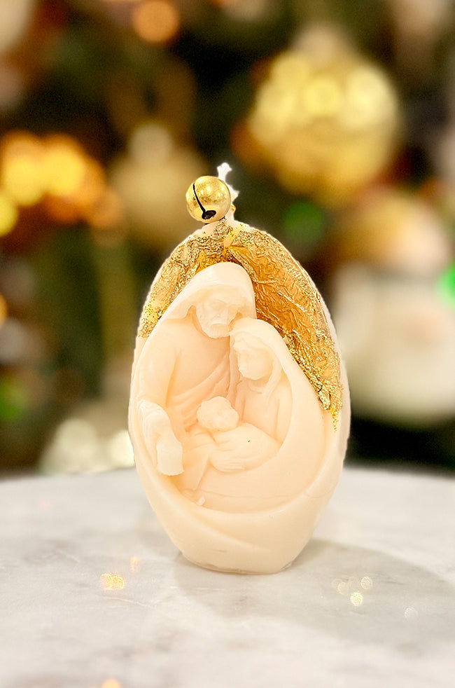 Nativity Glow Candle: Nativity Glow Christmas candle with Holy Family relief, gold leaf accent, and gold bell on top.