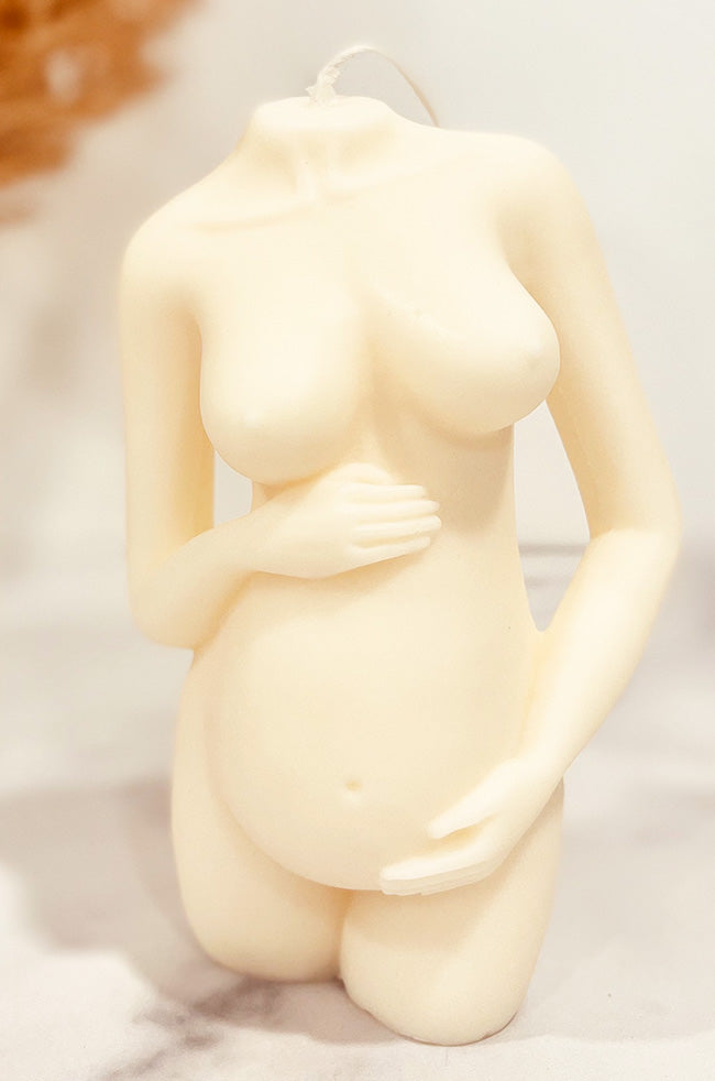 Precious Pregnant Venus Candle: sculptural pregnancy candle in ivory, displayed on a marble surface with neutral floral décor.