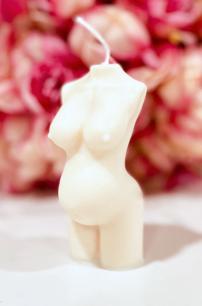 Pregnant Venus Candle: Front angled view of the ivory Pregnant Venus sculptural pregnancy candle with pink flowers.
